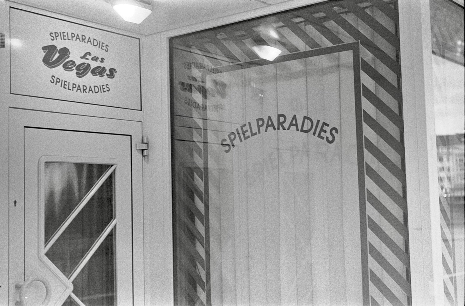 Shuttered amusement arcade doorway lettered Spielparadies Las Vegas, blinds drawn behind the glass