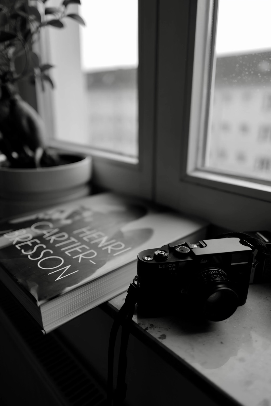Leica M6 resting on a windowsill next to a Henri Cartier-Bresson book and a potted plant
