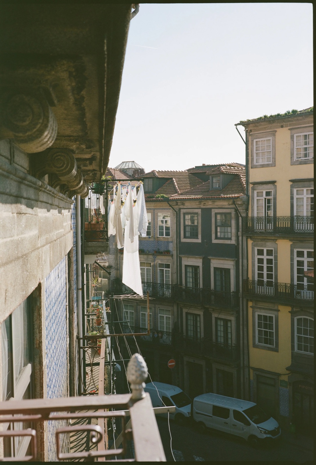 Laundry drying on a line strung between tiled balconies above a narrow street