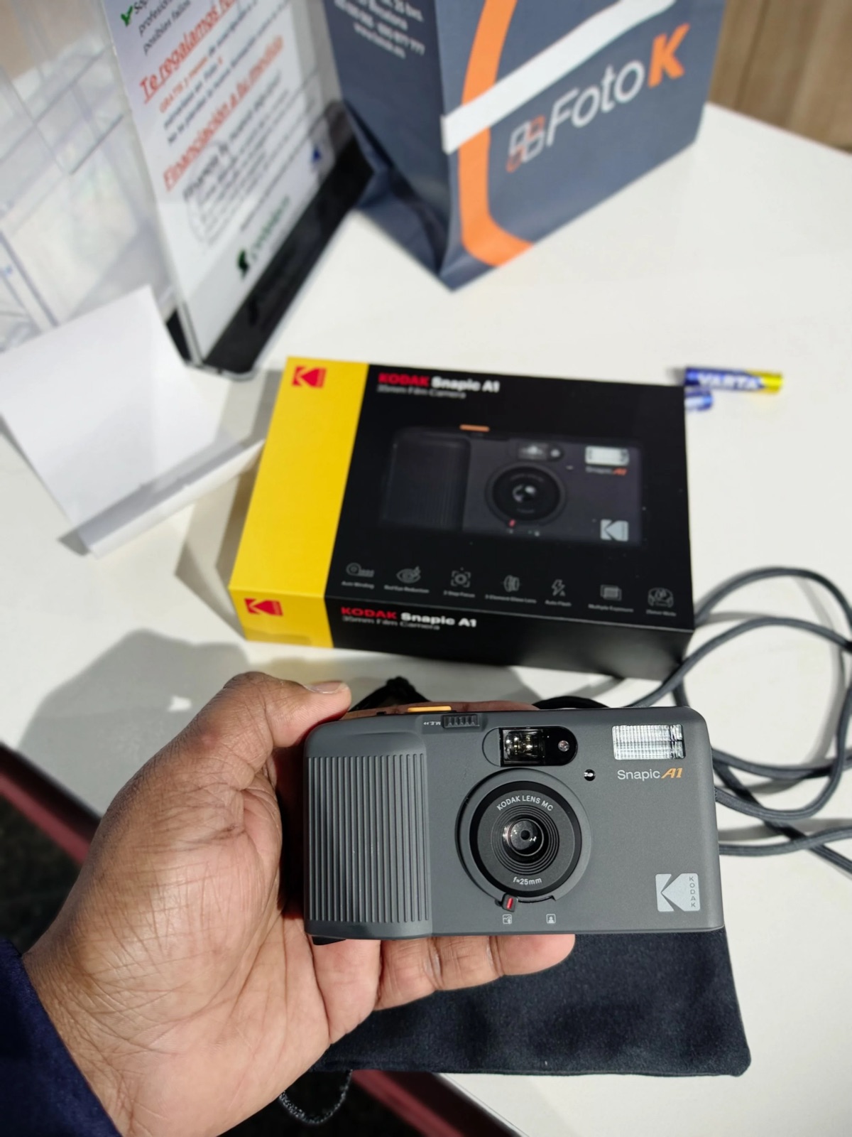 Hand holding a grey Kodak Snapic A1 film camera in front of its opened box on a shop counter