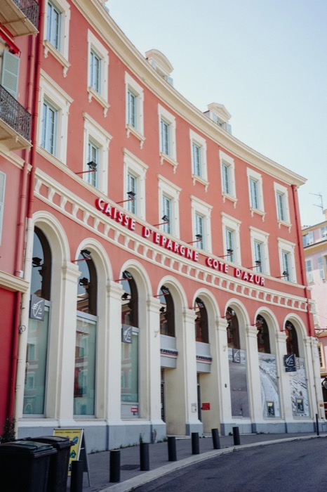 Curved pink bank building with arcaded ground floor and Caisse d'Epargne Cote d'Azur lettering