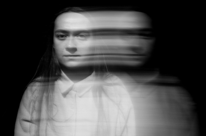 Long-exposure portrait against black: a woman's face sharp on the left, smeared into a blur to the right