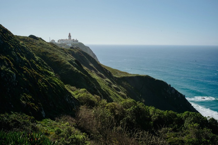 Green clifftop headland above the Atlantic with a small white lighthouse on the point