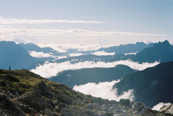 Tiny figures on a grassy summit above a sea of cloud filling the valleys beyond