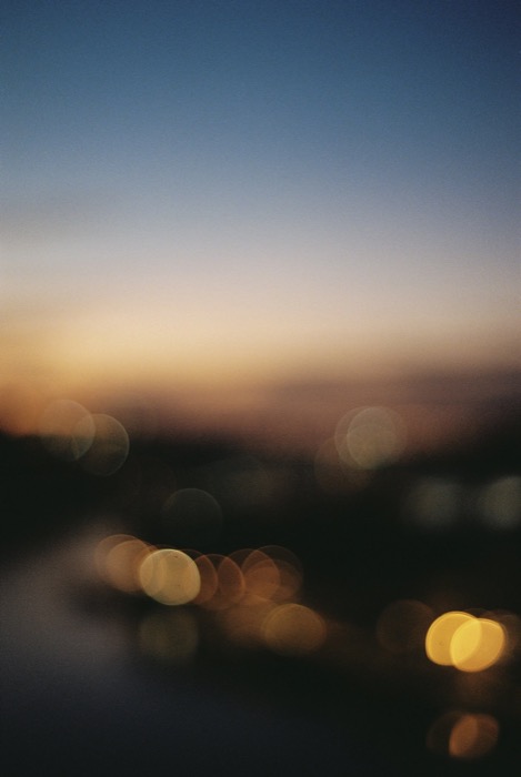 Out-of-focus city lights as round golden bokeh below a gradient dusk sky