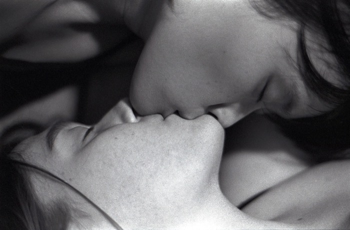 Tight, grainy close-up of two people kissing, faces filling the frame
