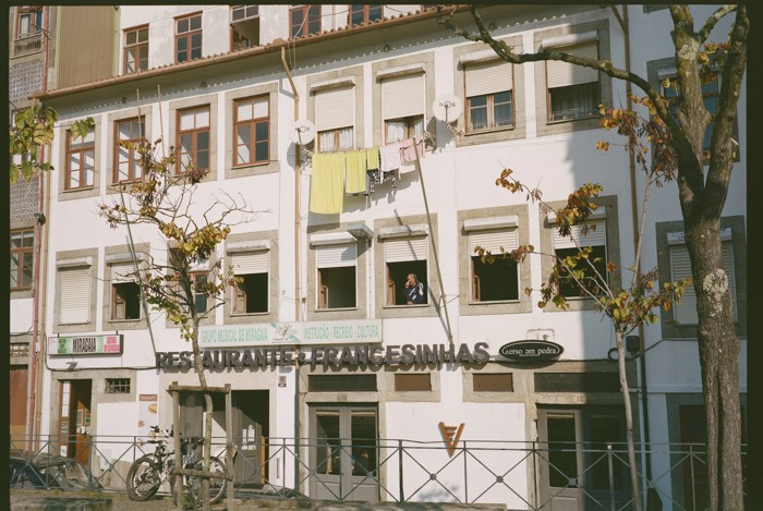 Man leaning from an upper window above a restaurant sign, towels drying on a line across the facade