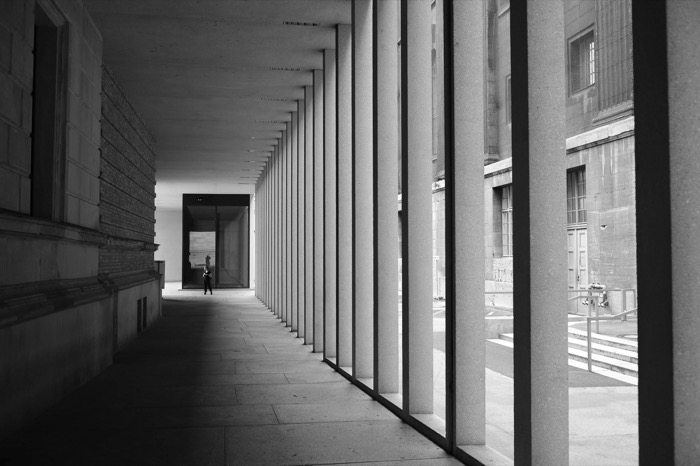 Long colonnade of concrete pillars, a single small figure standing at the far end