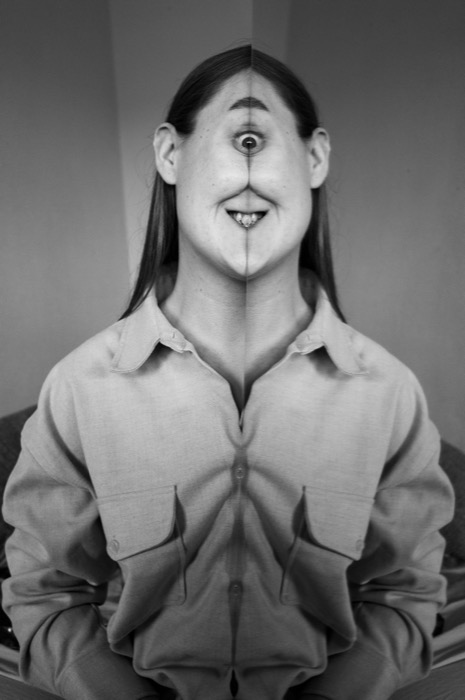 Mirrored portrait of a seated woman, the doubled halves giving her a single central eye and grinning mouth
