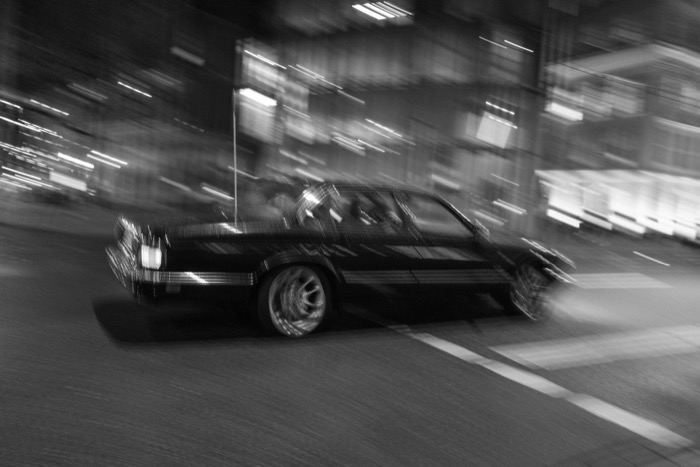 Old saloon car sweeping through a night street, background smeared into streaks of light