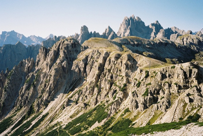 Jagged limestone spires and scree ridges of a high mountain range under clear sky