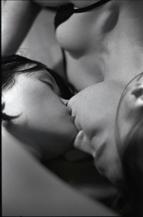 Close, grainy frame of two people kissing, shoulders and jawlines filling the picture
