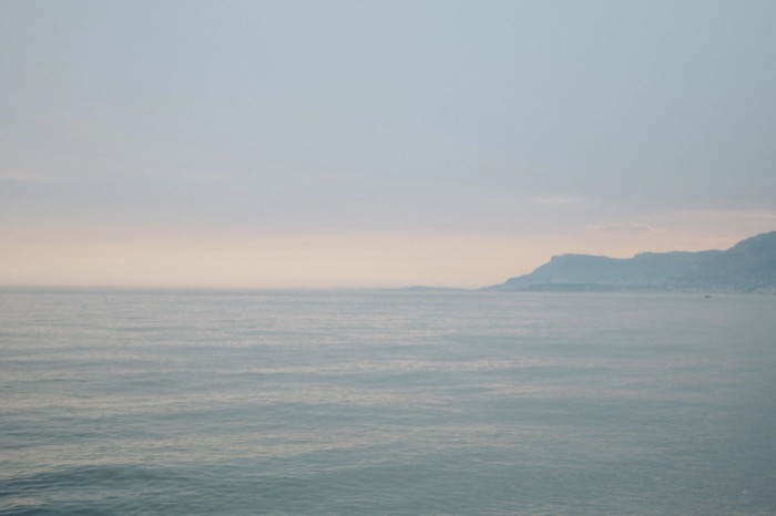 Hazy pastel sea meeting a faint headland, almost empty horizon