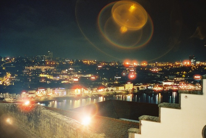 City lights along a river at night, big circular lens flares floating over the dark sky