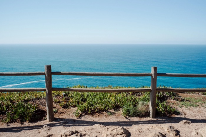 Weathered wooden fence on a clifftop above an open blue ocean stretching to the horizon