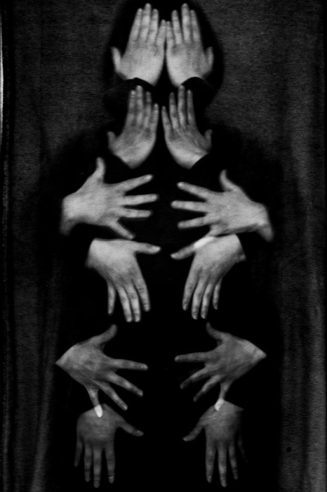 Multiple exposure of pale hands pressed against a dark body, palms stacked from face to feet